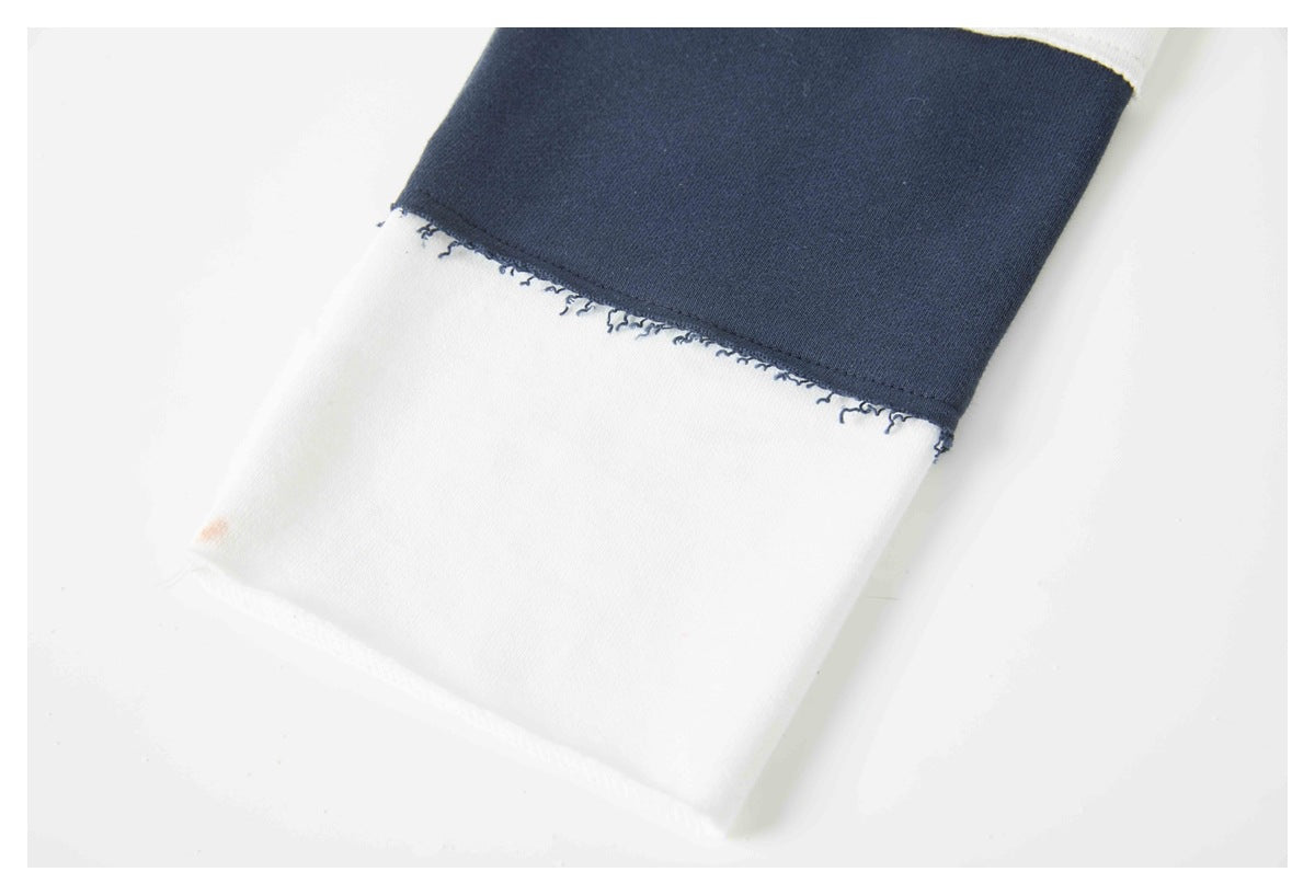 Close-up of a white garment cuff or hem adjoining a navy fabric panel.