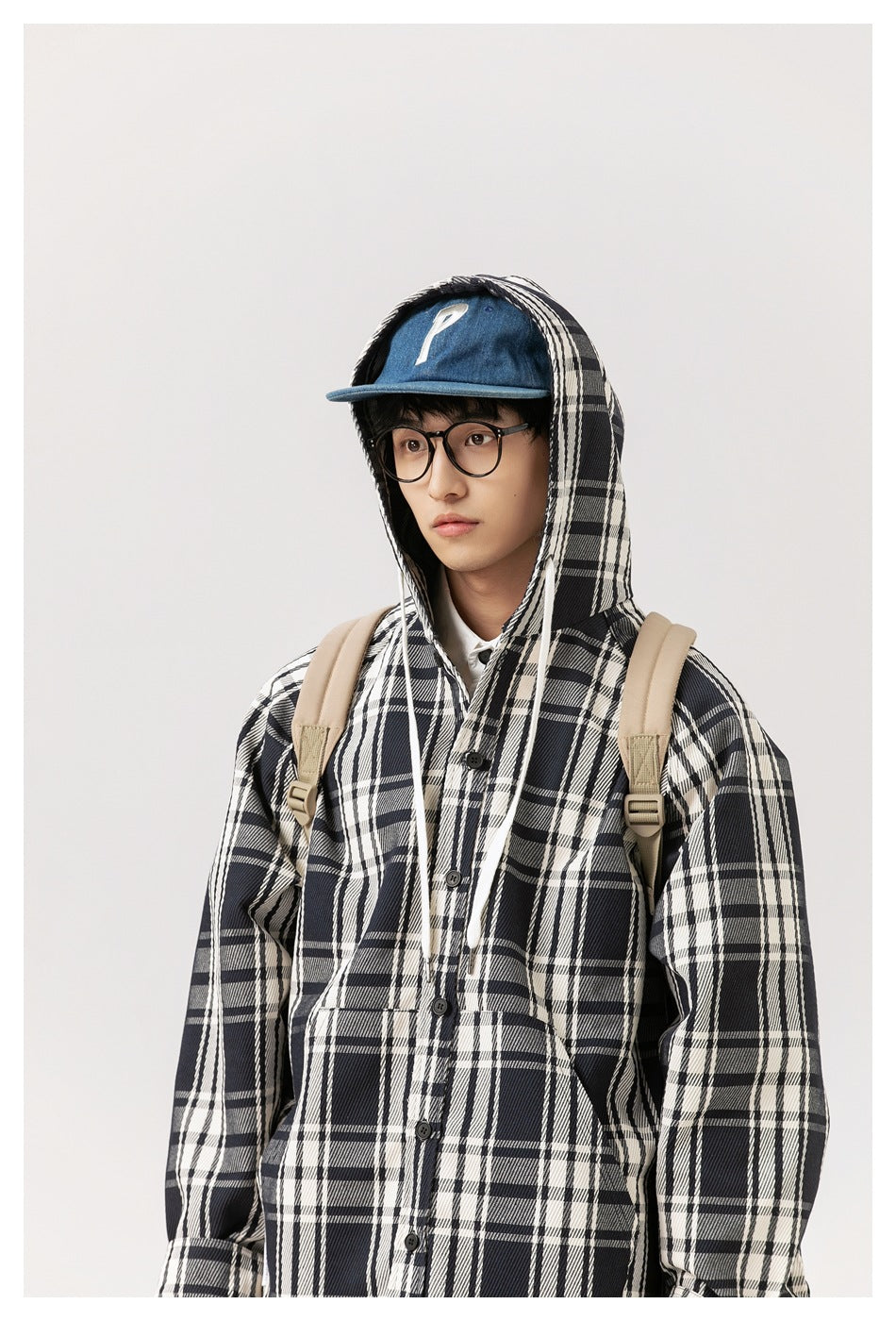 Model wearing the black-and-white plaid coat with its hood raised and white drawstrings visible.