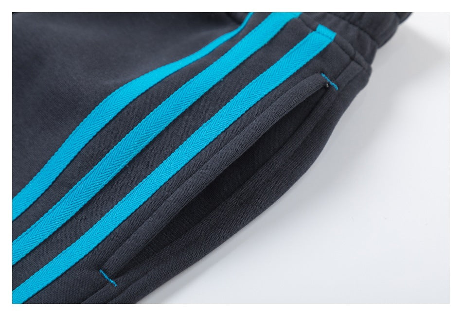 Close-up of three blue stripes and a welt pocket on charcoal jogger pants.