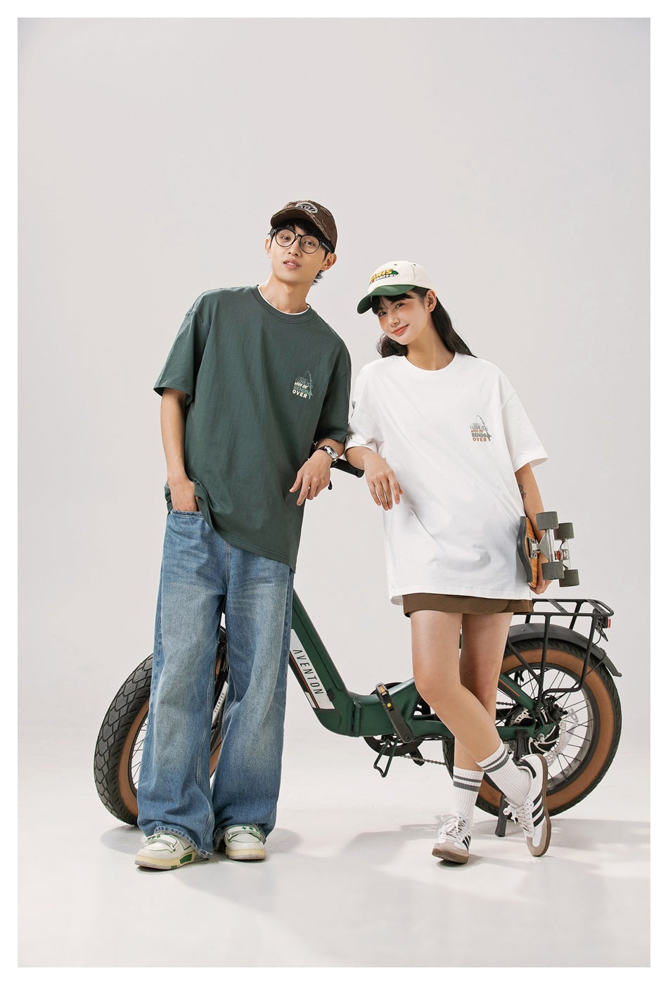 Two models show oversized dark green and white graphic T-shirts from the front.