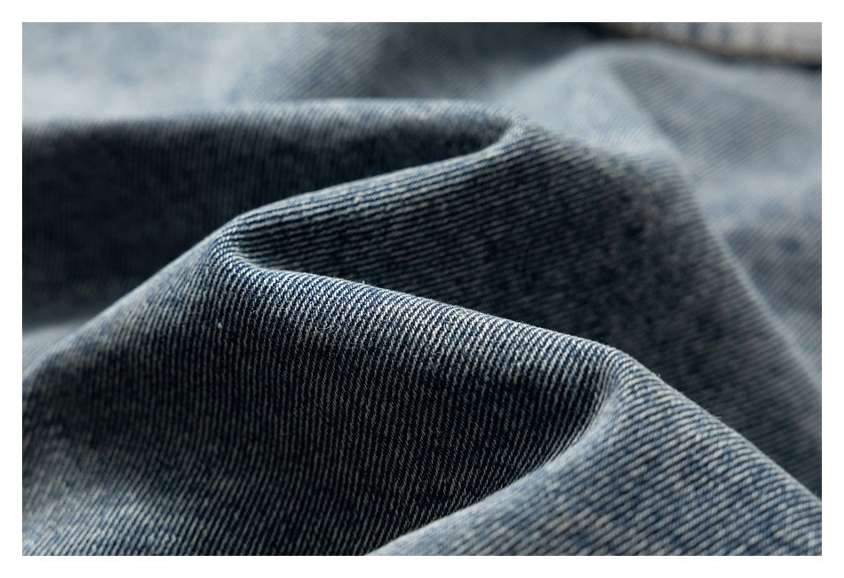 Close-up of dark blue denim gathered into folds, showing its diagonal weave and texture.