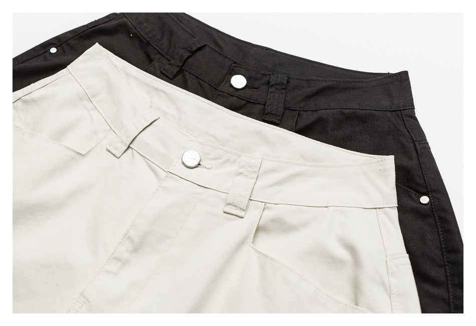 Close-up of cream and black shorts waistbands with belt loops, metal buttons and front pocket seams.