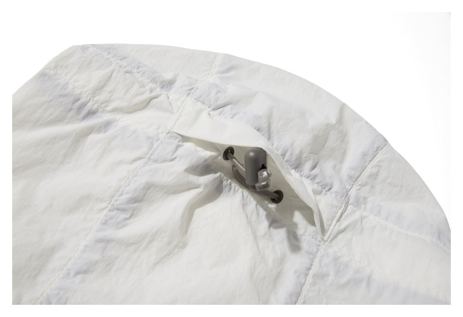 Close-up of white garment fabric with stitched panels and a dark cord toggle fastening.