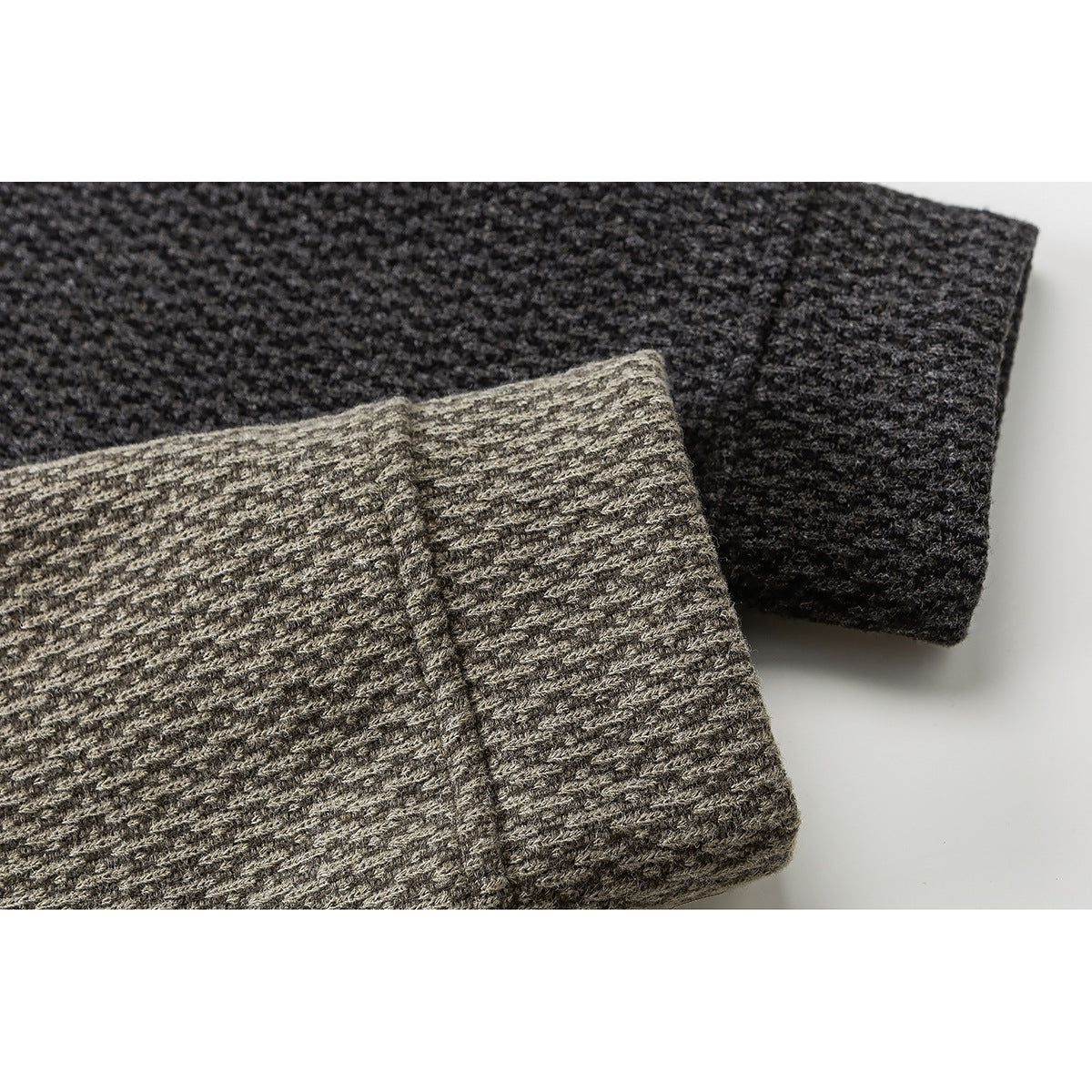 Close-up of folded sleeve cuffs showing the textured knit in taupe-gray and charcoal colorways.