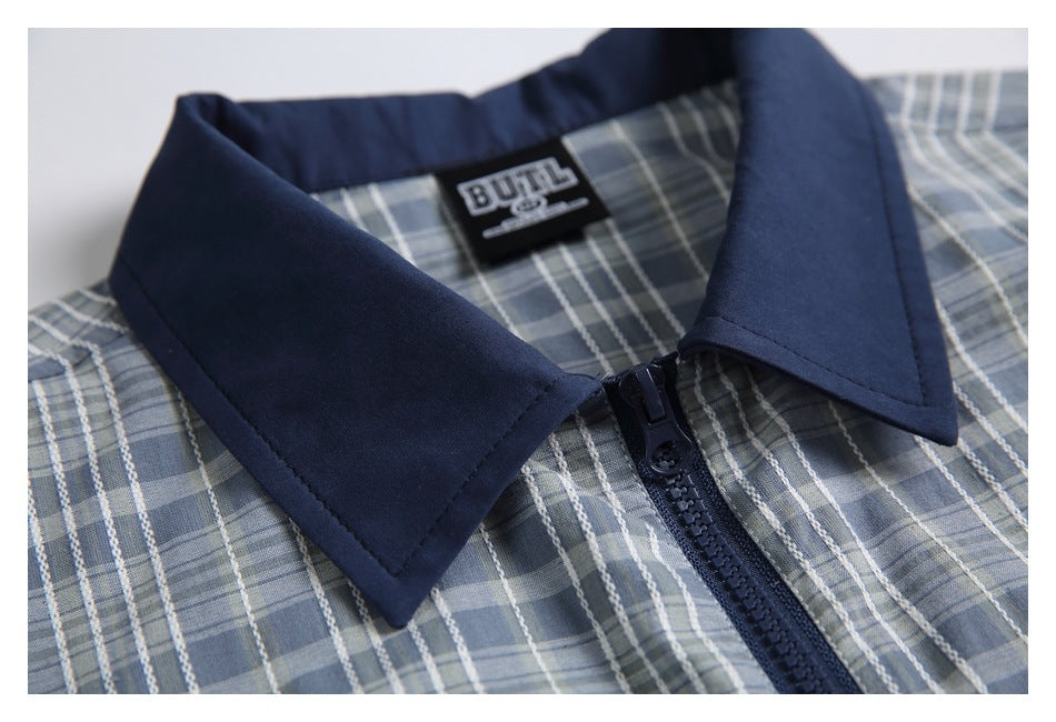 Close-up of the jacket's navy collar, zipper and blue-gray plaid fabric, with a sewn neck label.