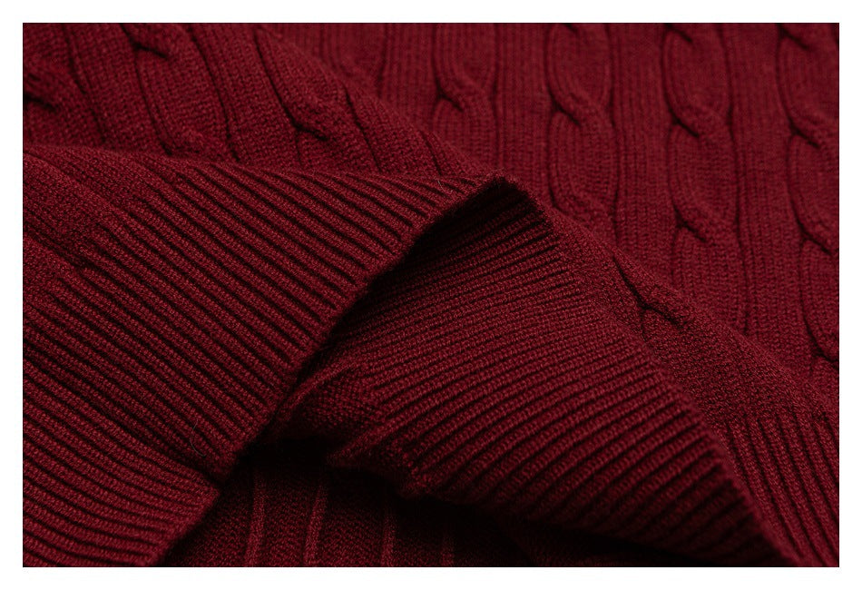Close-up of a burgundy cable-knit sweater with a folded ribbed cuff.