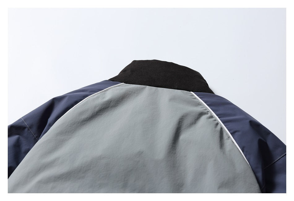 Close-up of a jacket's upper back with a light gray panel, navy sleeves, black collar, and white piping.