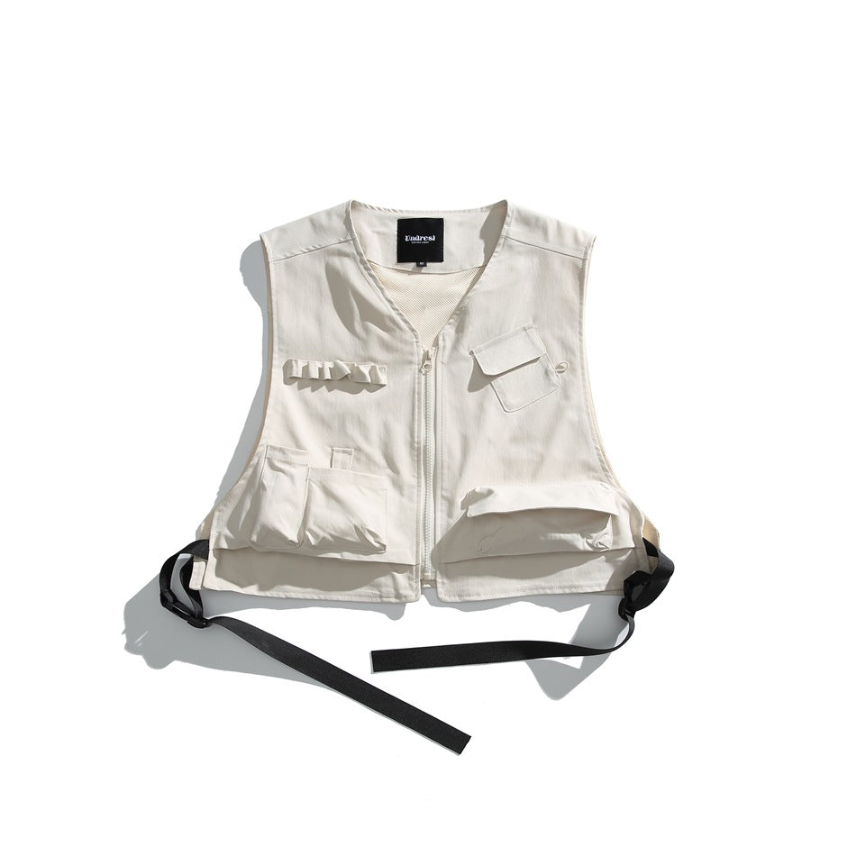 Off-white sleeveless utility vest flat lay with front zipper, multiple pockets and black buckled side straps