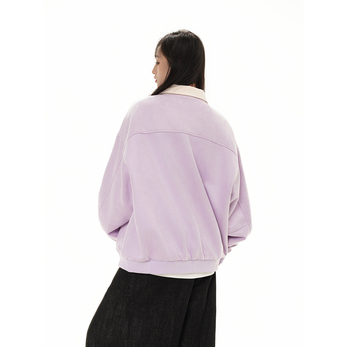 Back view of a model wearing a lilac jacket with a cream collar and ribbed hem, paired with black trousers.