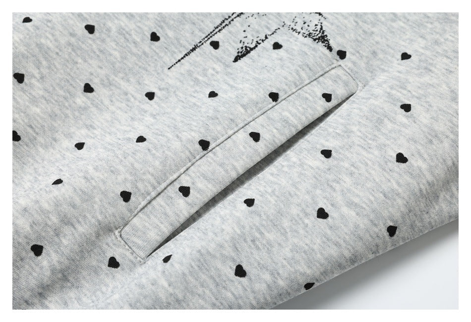 Close-up of a slanted welt pocket on light gray fabric patterned with small black hearts.