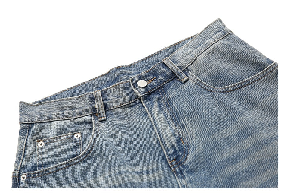 Angled close-up of light-wash jeans showing the front button, fly, belt loops and pockets.