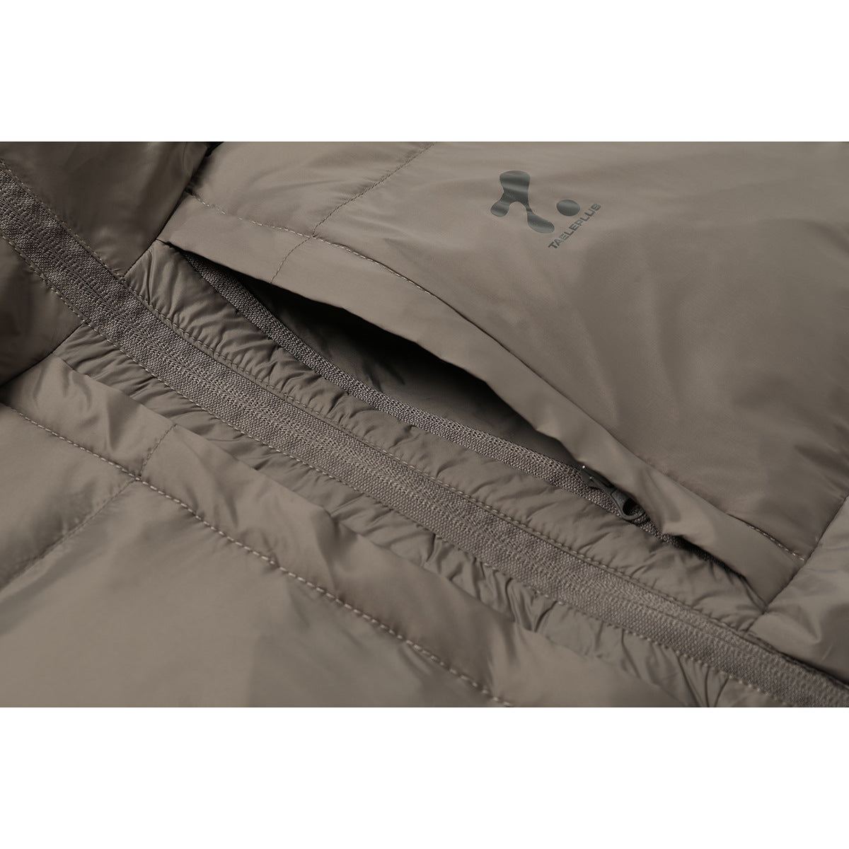 Close-up of the taupe puffer jacket’s zippered pocket and chest logo.