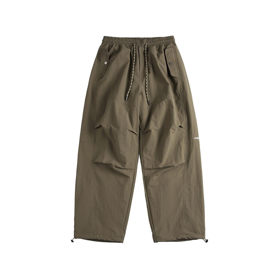 Front view of olive-brown cargo pants with an elastic drawstring waist, flap pockets, and wide legs.