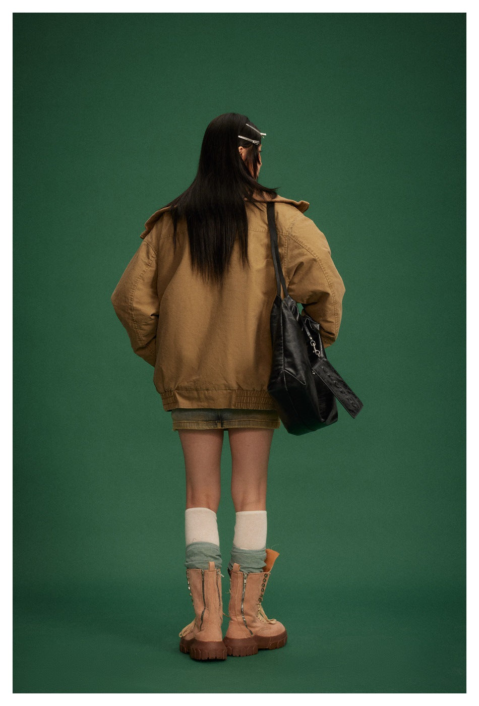 Back view of a model wearing a loose tan jacket with an elastic hem.
