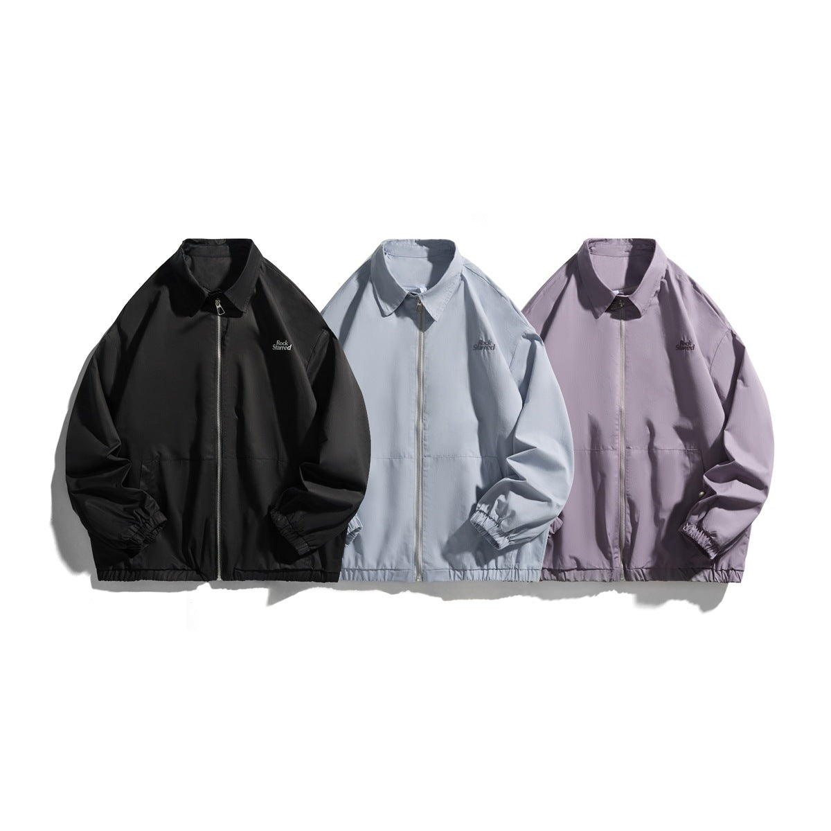 Three collared zip-front jackets shown from the front in black, light blue-gray and lavender.