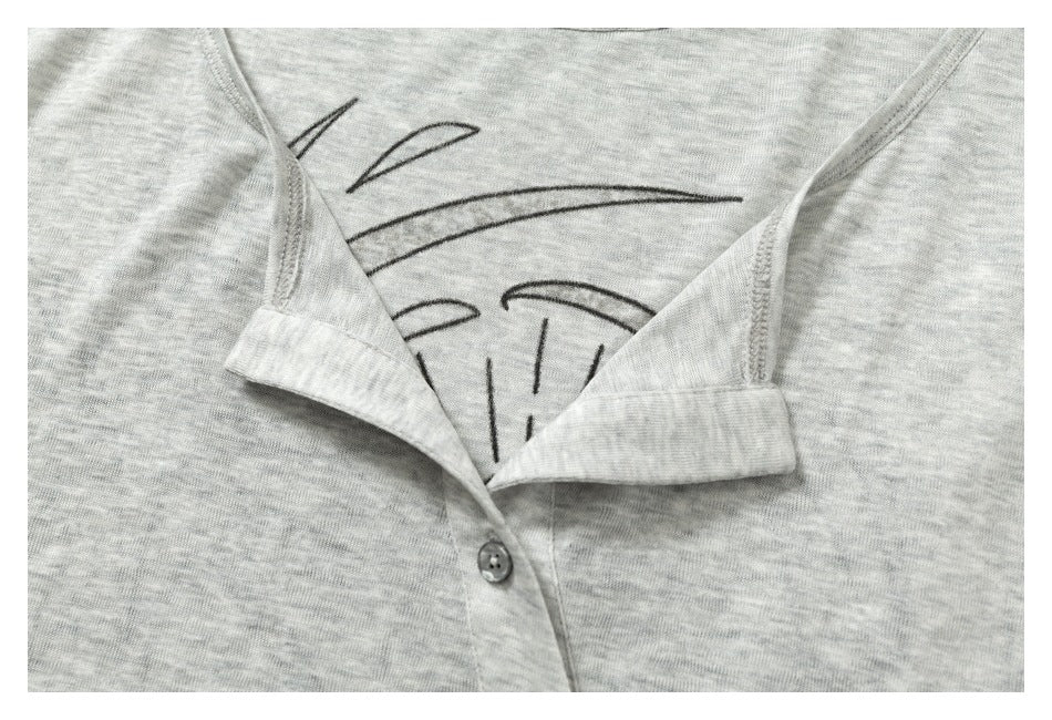Close-up of a light gray heather shirt's black line graphic and open button placket with a visible button.