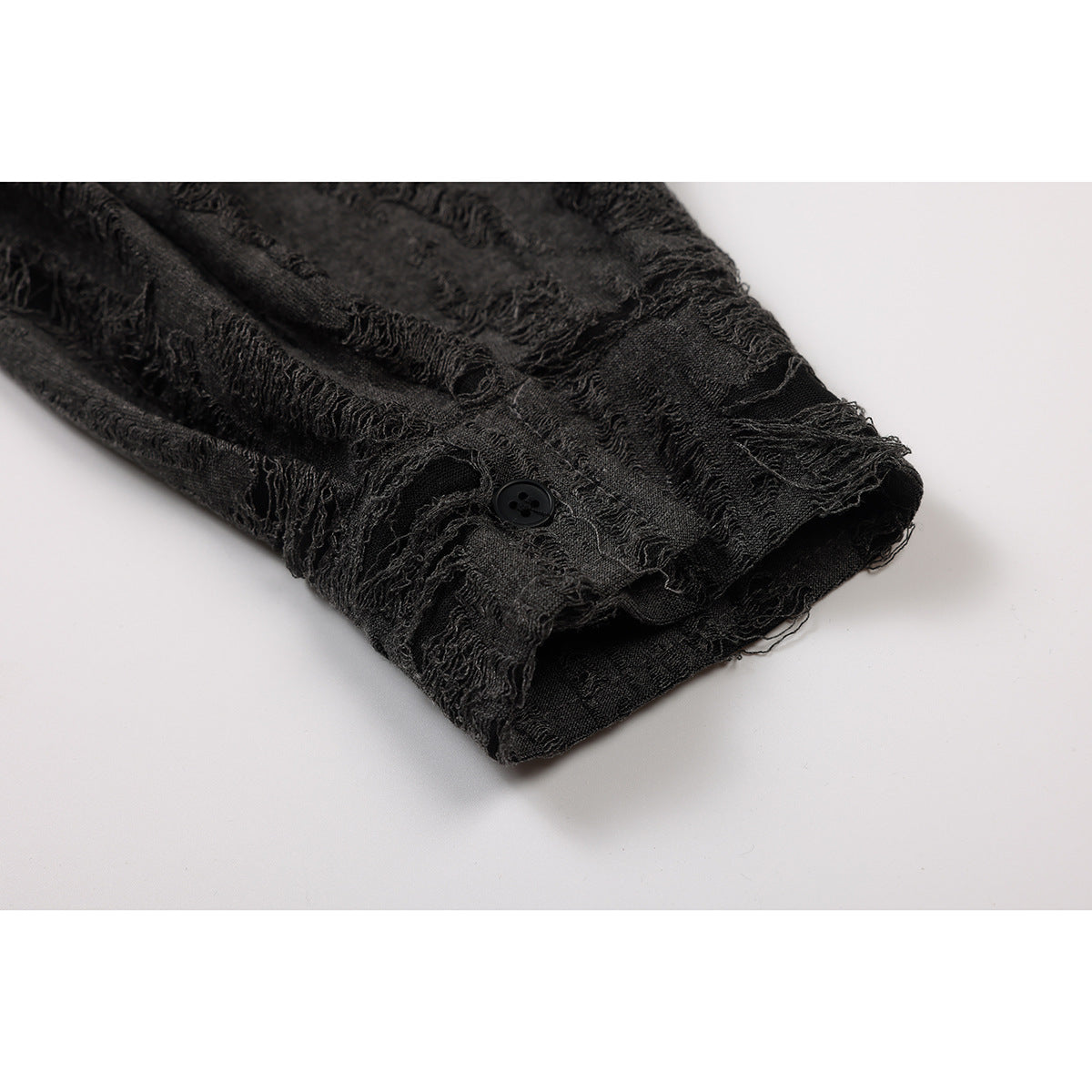 Close-up of a charcoal shirt sleeve cuff with a black button and distressed textured stripes.