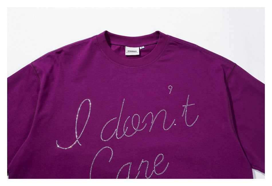 Close-up of a purple T-shirt with rhinestone “I don't care” script across the chest.