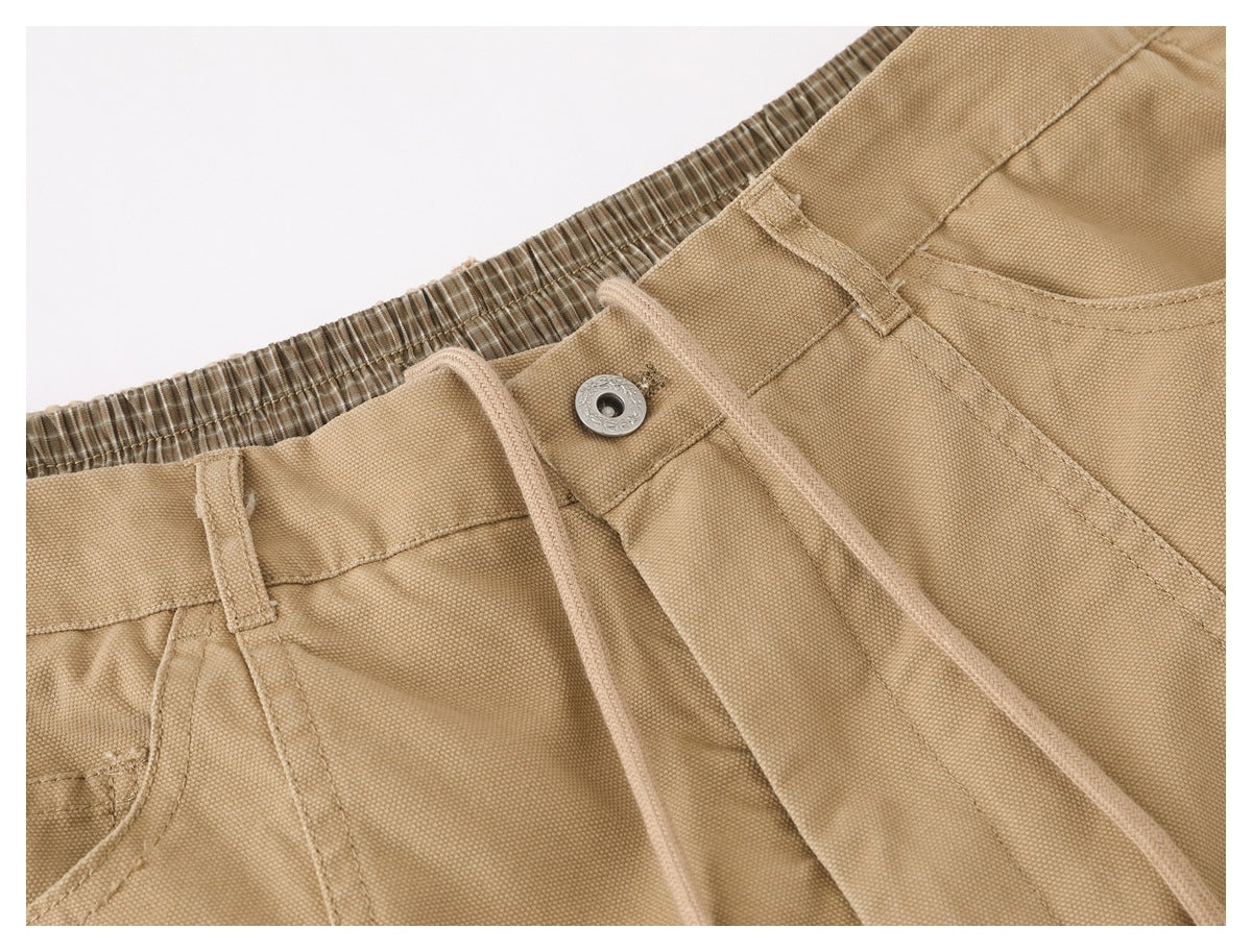 Close-up of the tan pants' drawstring waist, waistband, and front fastening.