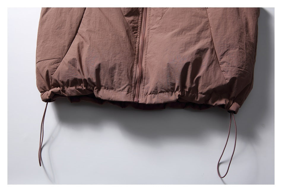 Close-up of the vest's gathered lower hem and two dangling adjustment cords.