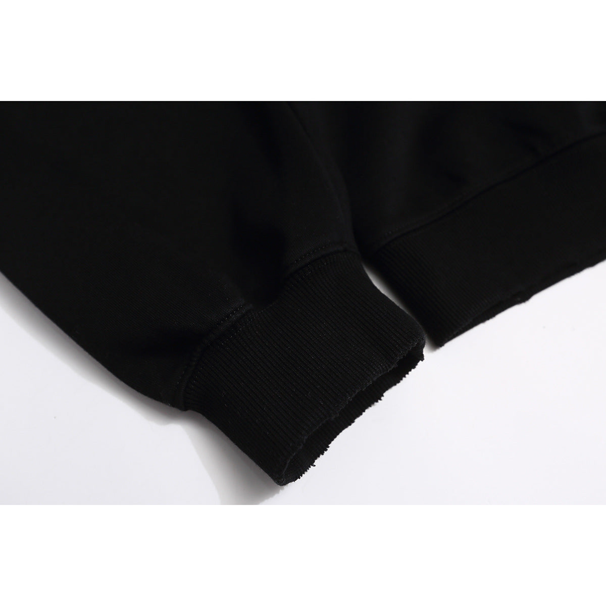 Close-up of a black sweatshirt sleeve ending in a wide ribbed cuff.