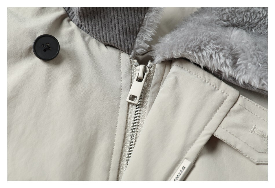 Close-up of a cream coat's front zipper, black button, gray ribbed collar, and fluffy lining.