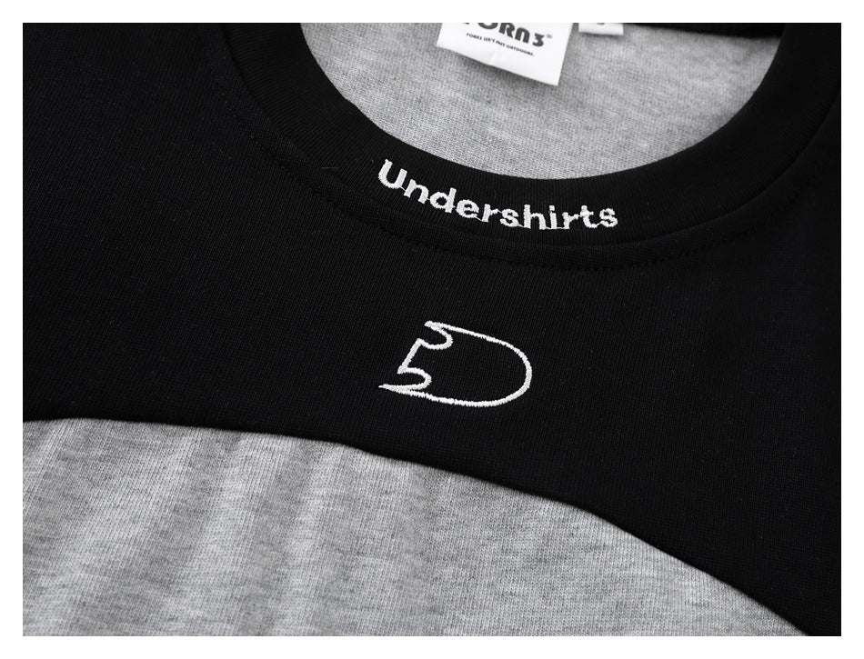 Close-up of a black neckline over gray fabric, with white “Undershirts” lettering and a small white emblem.