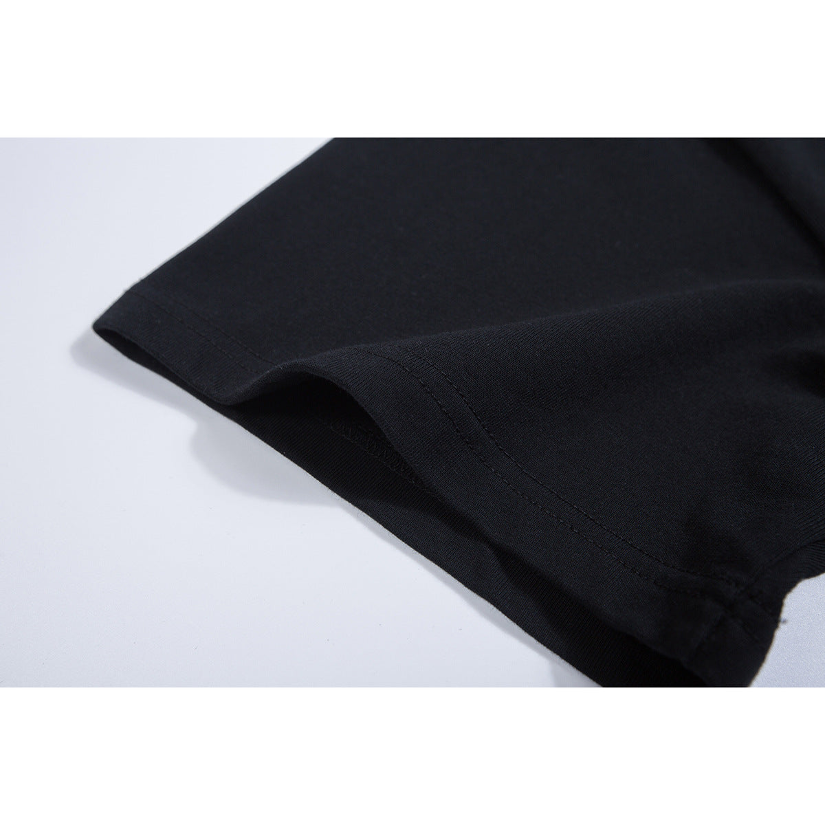 Close-up of a black T-shirt sleeve edge and stitched seam.