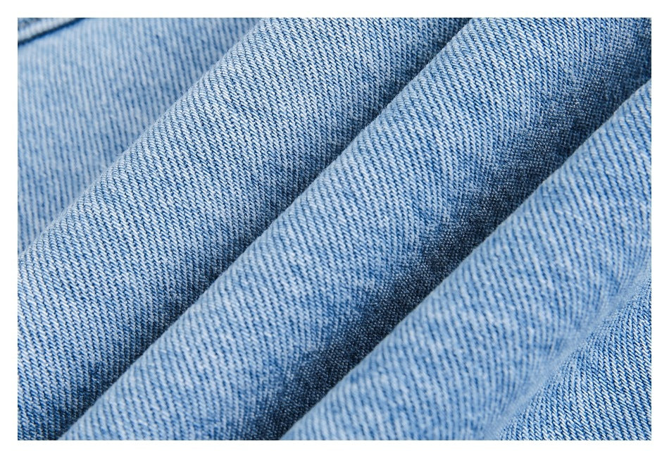 Macro view of light blue denim fabric folded to show its diagonal weave and texture.