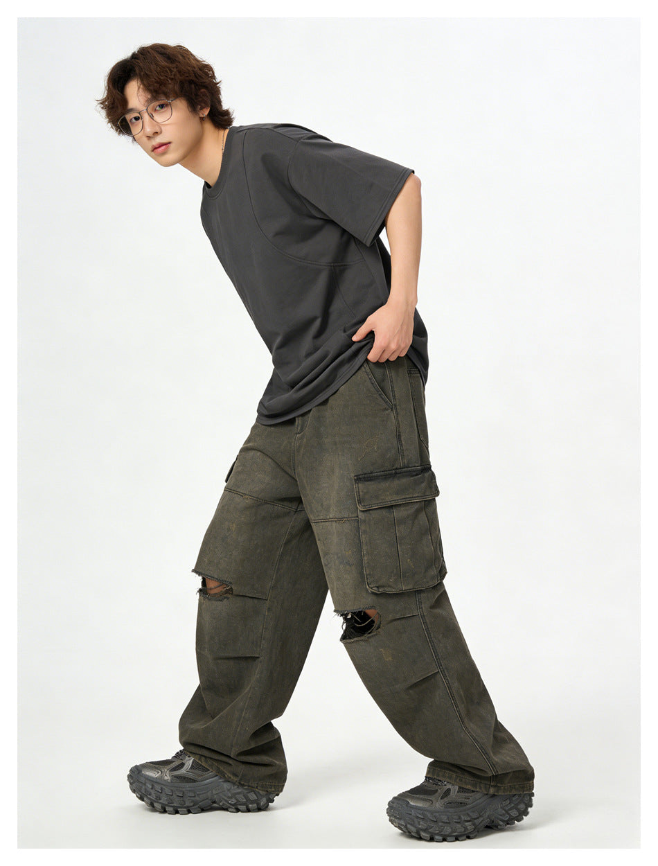 Model in a charcoal-gray oversized T-shirt and olive-gray cargo pants, leaning forward in a walking pose.