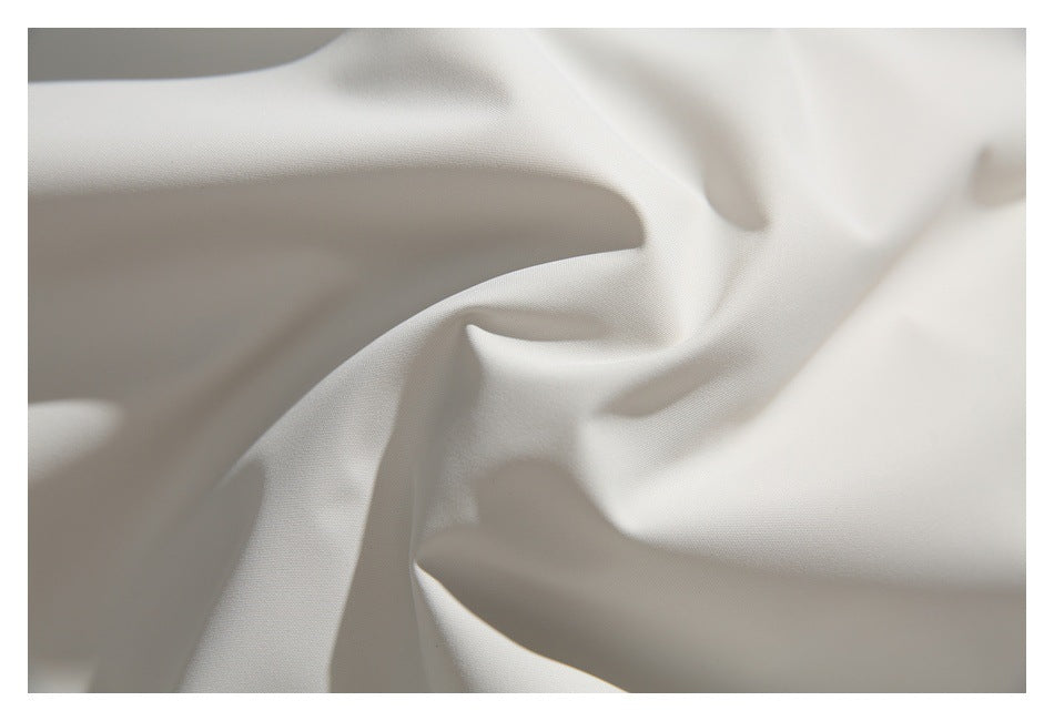 Extreme close-up of ivory fabric draped into soft folds, showing its fine surface texture.