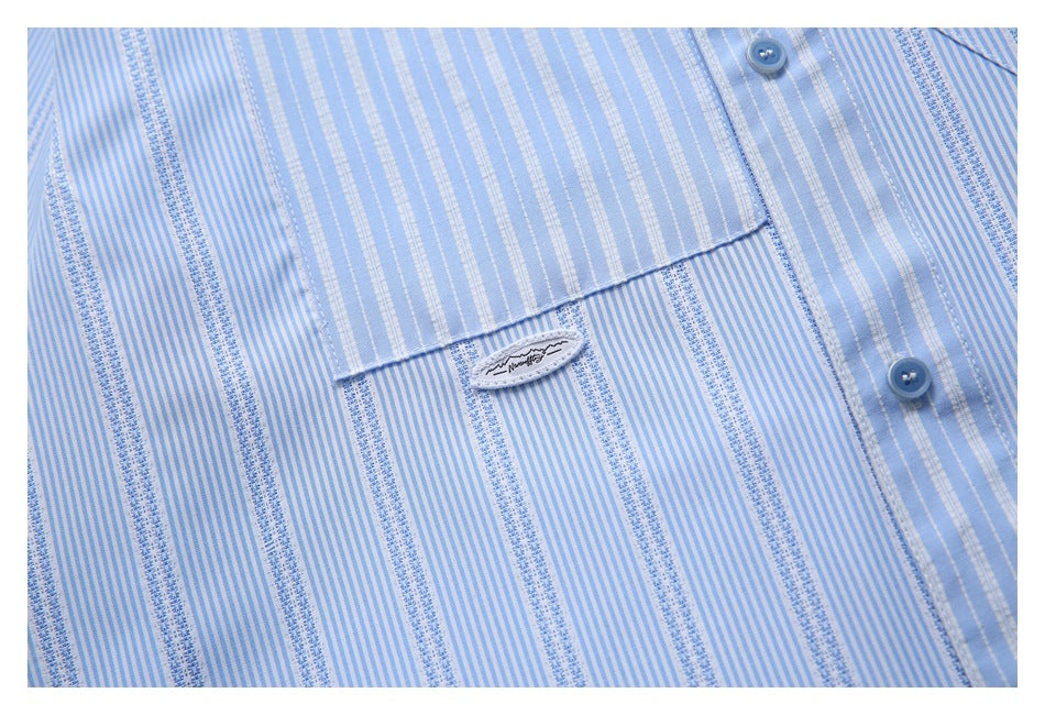 Close-up of a light blue striped shirt pocket, blue buttons, and a small sewn label.