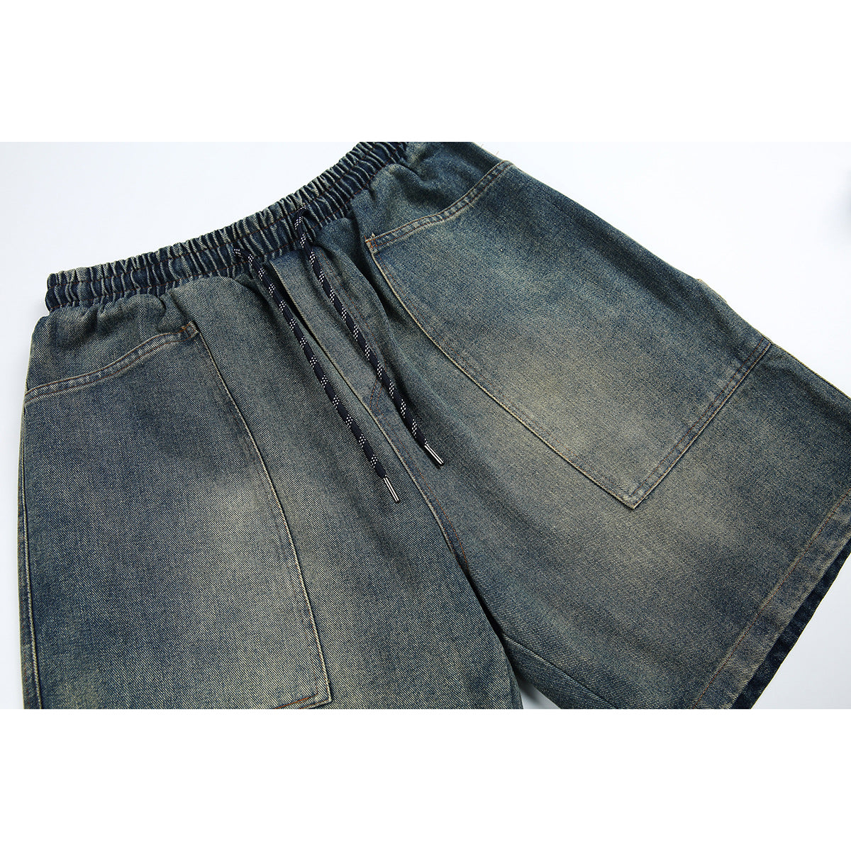Angled close-up of blue-gray denim shorts with an elastic drawstring waist and large front pockets.