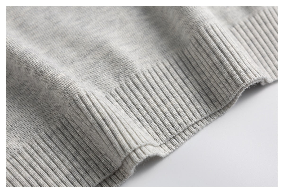 Close-up of the light gray knit polo's ribbed bottom hem.