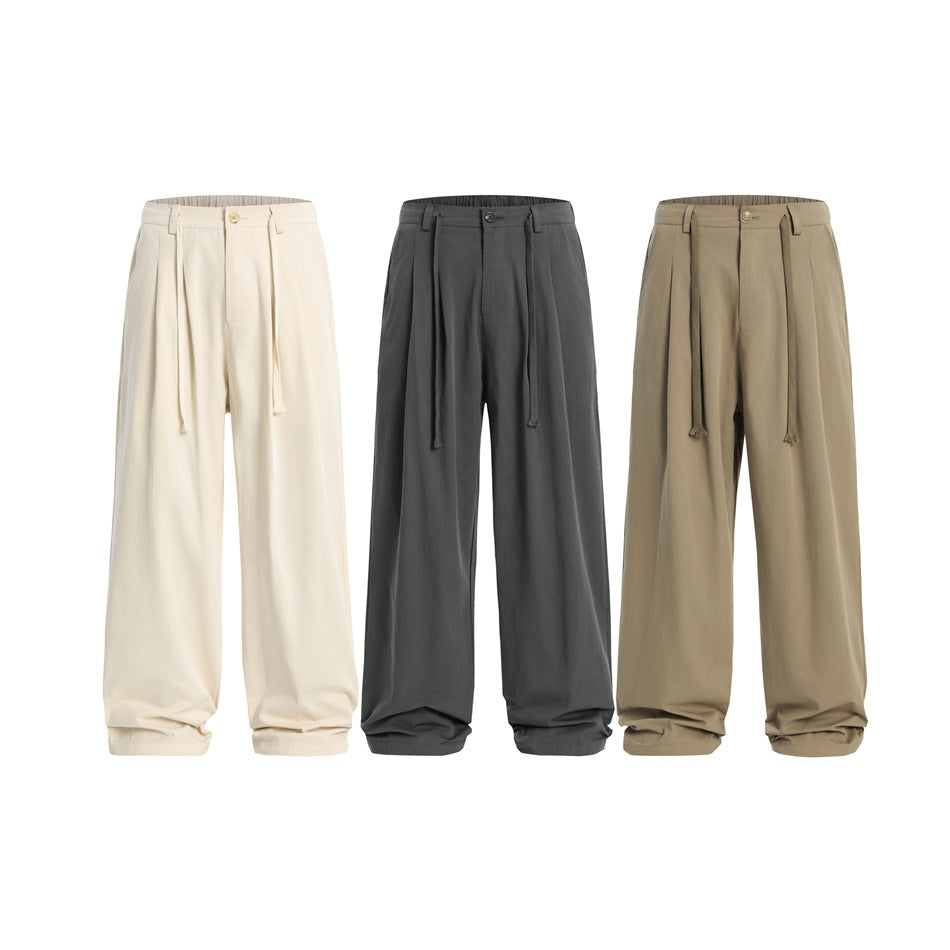 Three front views of wide-leg drawstring trousers in cream, charcoal, and khaki.