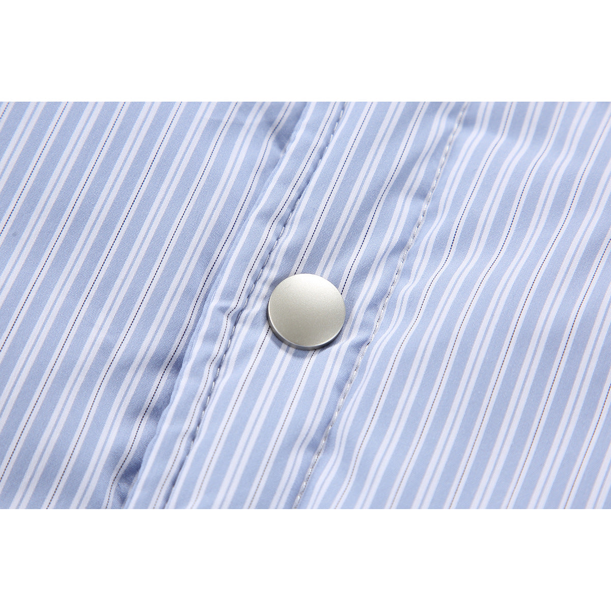 Close-up of a silver snap button and stitched placket on light blue and white striped fabric.