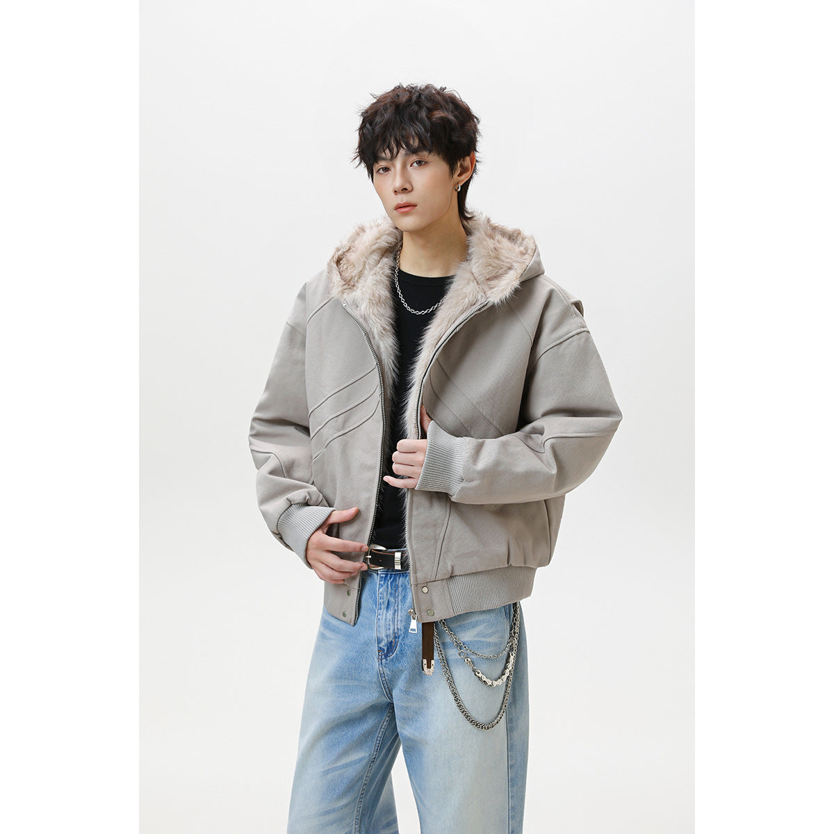 Model wearing a taupe-gray hooded jacket with pale faux-fur lining, ribbed cuffs and hem, and diagonal panel seams.
