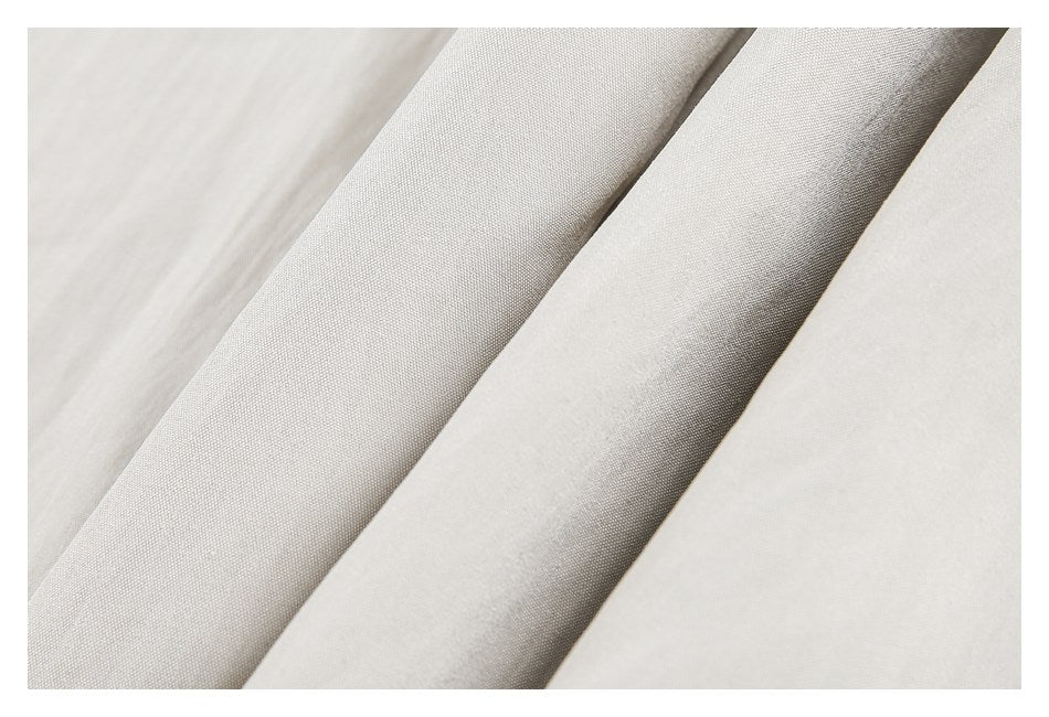 Close-up of light beige garment fabric and a folded edge showing its weave.