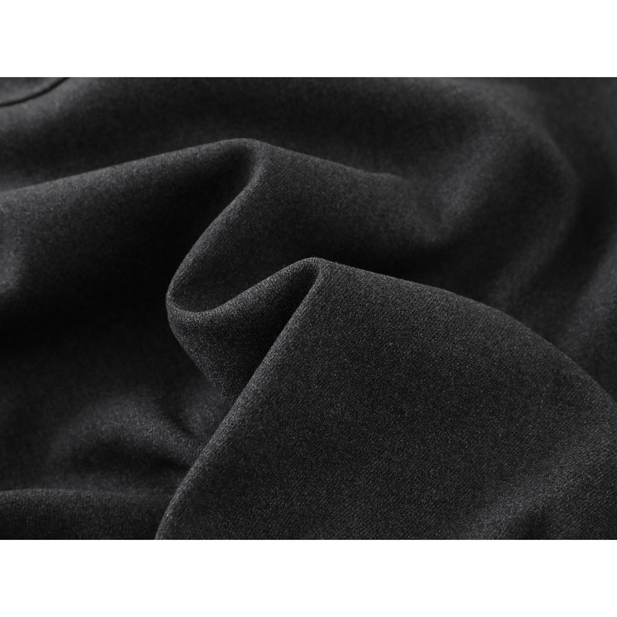 Close-up of dark charcoal jacket fabric folded to show its surface and drape.