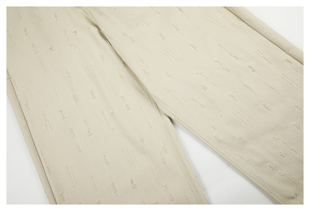 Close-up of cream trouser legs displaying scattered raised stitch marks and the leg seams.