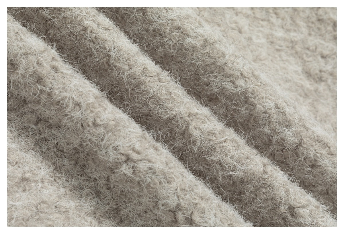 Close-up showing the soft, fuzzy surface and folds of a light beige garment.