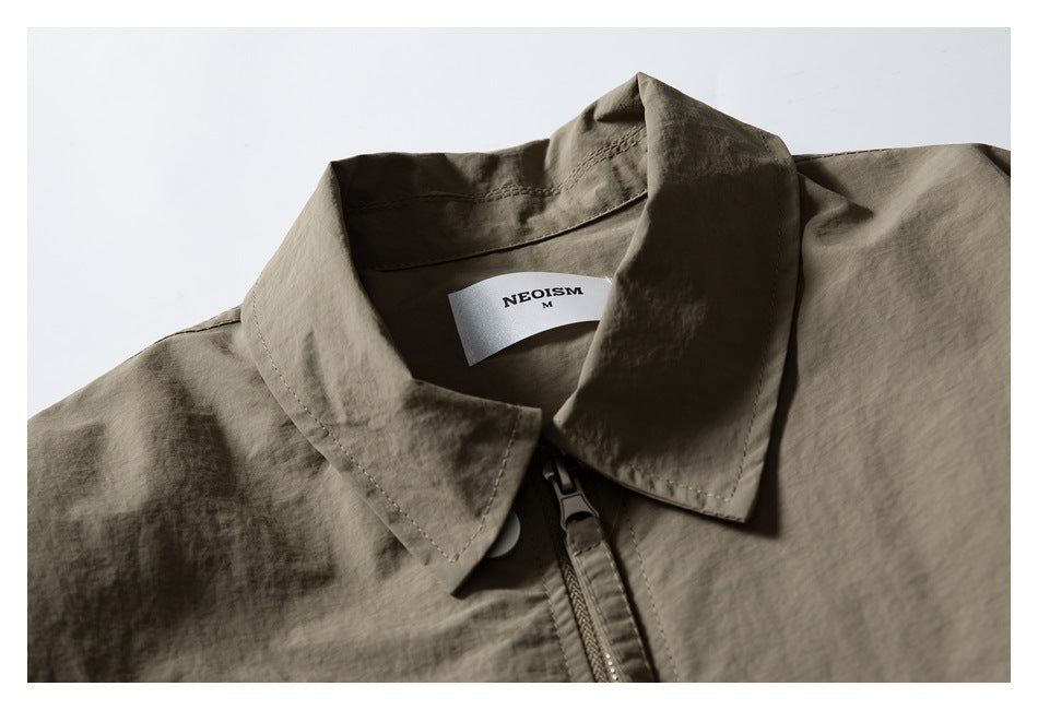 Close-up of an olive-gray jacket's pointed collar, zipper, and sewn-in neck label.
