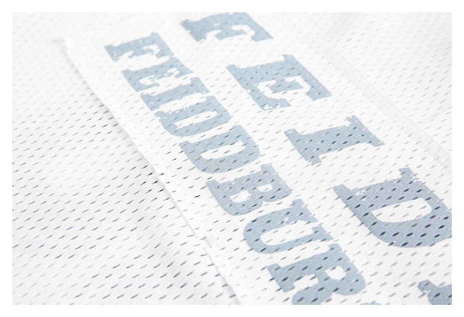 Close-up of white perforated mesh with distressed pale blue lettering printed on the garment.
