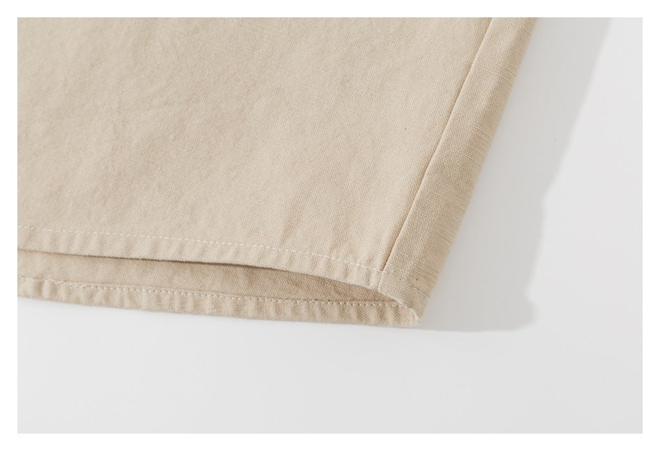 Close-up of the stitched hem and side seam of a beige shirt.