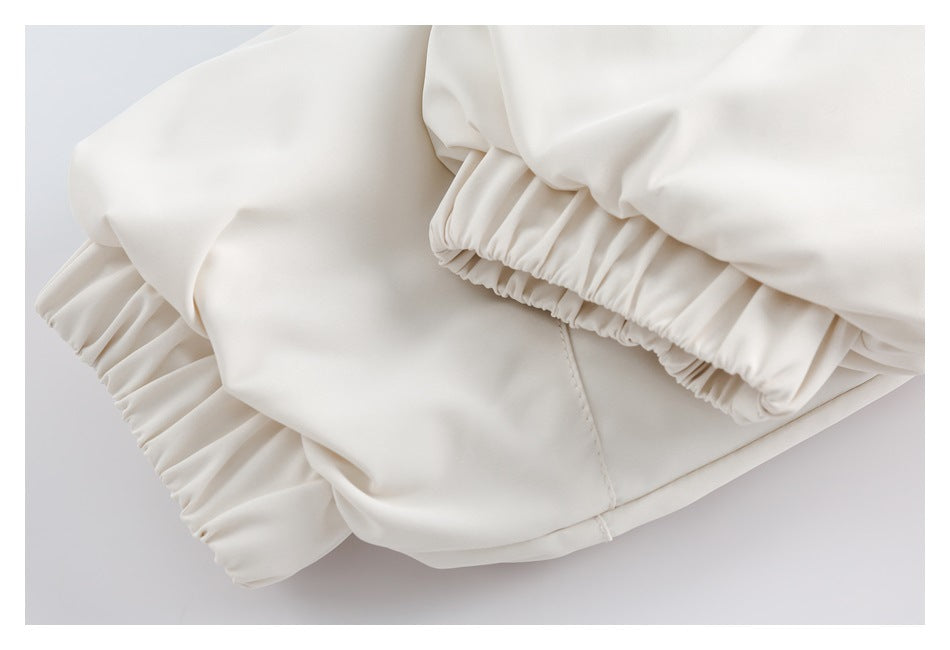 Close-up of a white garment with gathered elastic cuffs and visible stitching.