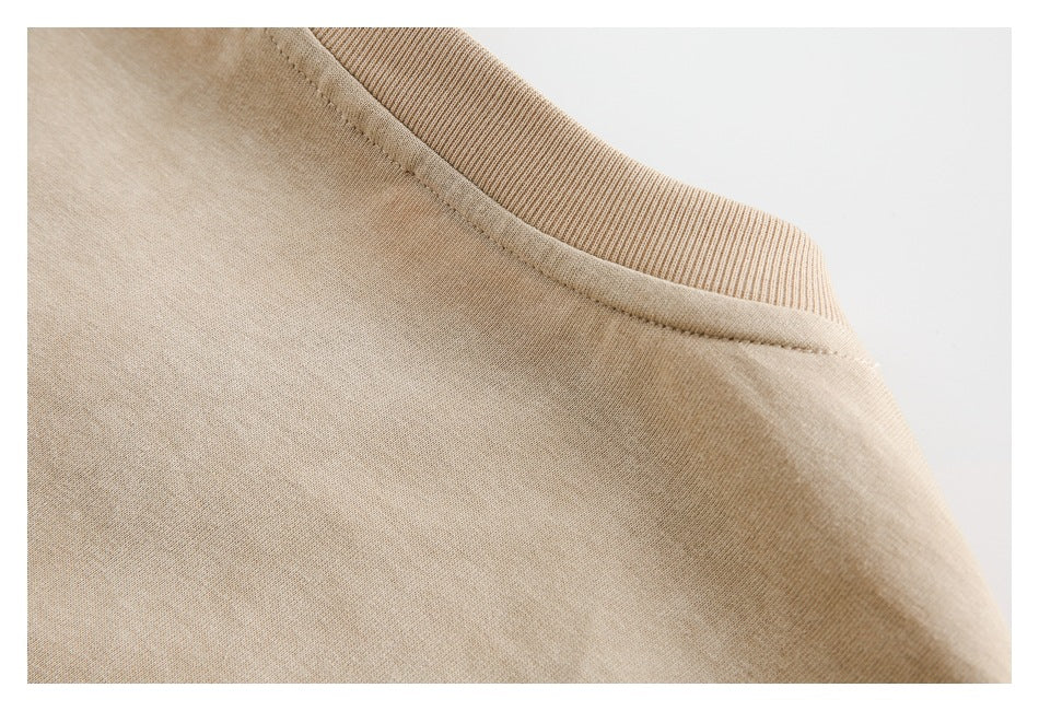 Close-up of the beige T-shirt shoulder and ribbed neckline stitching.