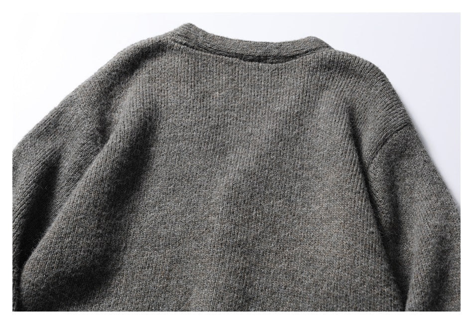 Back view of a charcoal gray knit cardigan laid flat, showing its plain back and long sleeves.