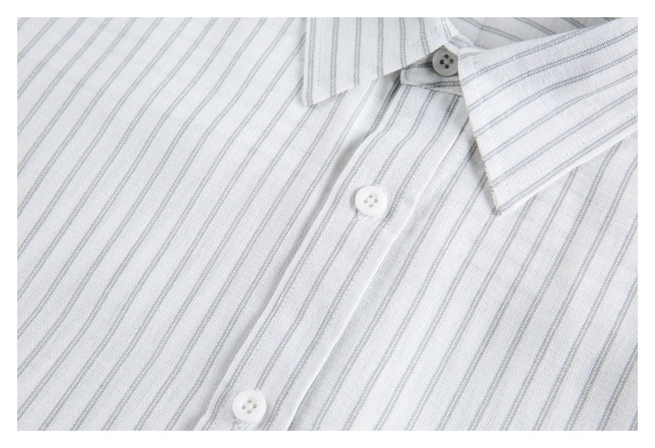 Close-up of a white shirt with fine gray stripes, showing the button placket and pointed collar.
