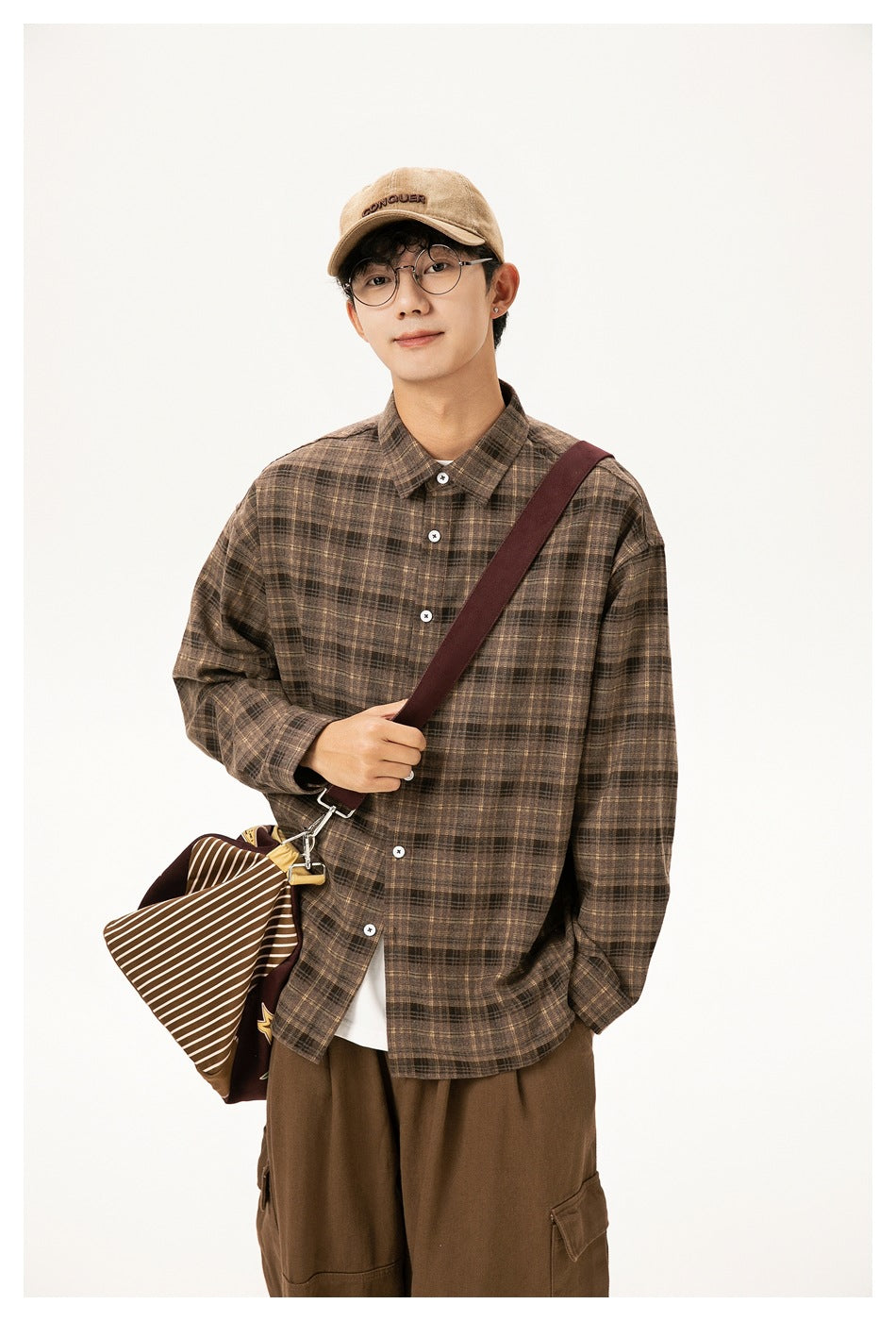 Model wearing a brown plaid button-up shirt over a white tee, with a crossbody bag and brown cargo pants.