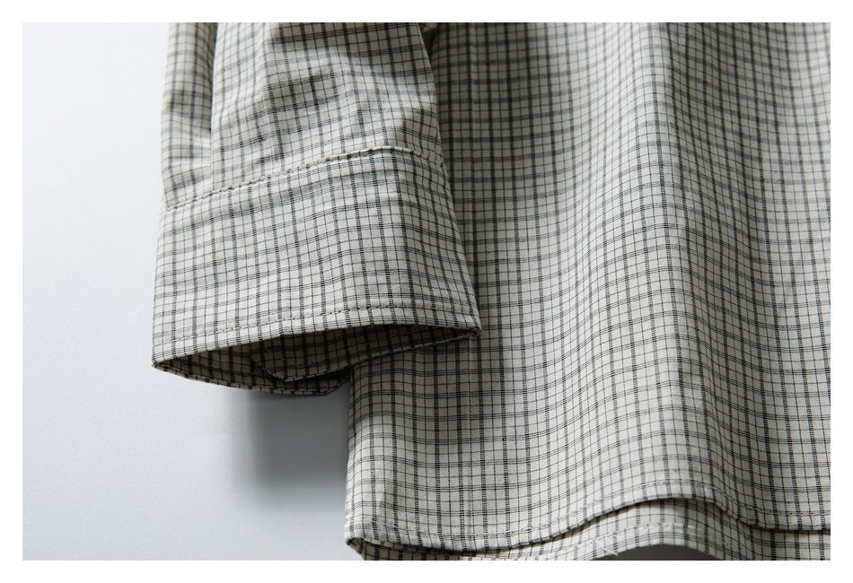 Close-up of a checked shirt sleeve hem and curved lower edge in off-white, black, and gray.